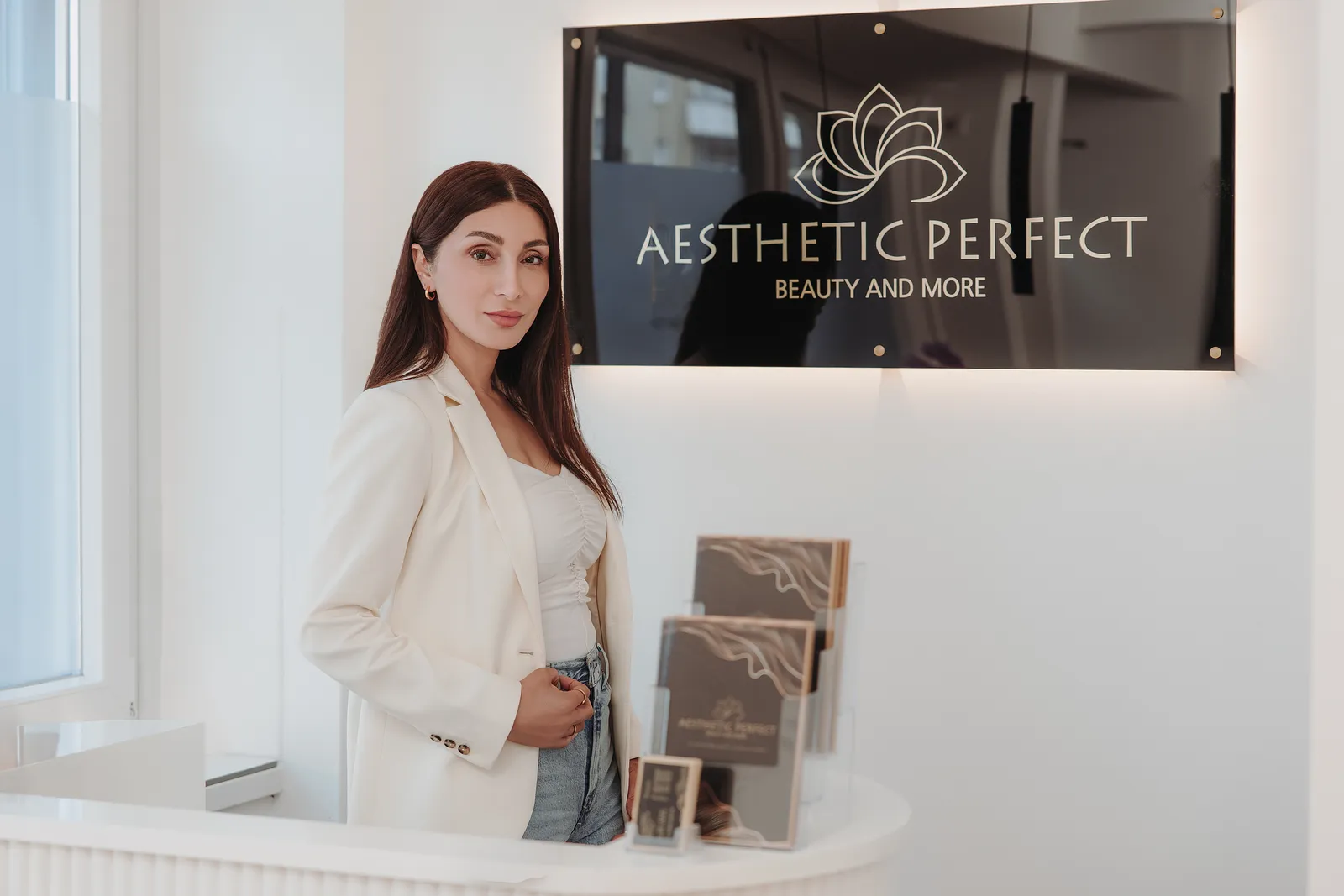 Zeliha Colak am Empfang von Aesthetic Perfect unter dem goldenen Logo